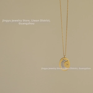 Macro detail of oval two-tone pendant featuring moon and star on 18K gold plated chain
