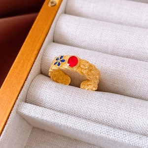 Macro detail of gold flower ring with red stone and blue enamel in jewelry box