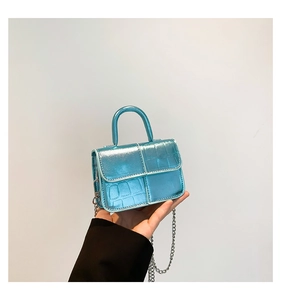Close-up of metallic blue mini handbag featuring crocodile texture and silver chain strap