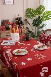 Detail of red Christmas tablecloth featuring white Merry Christmas text and snowflake patterns