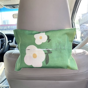Detail of green linen tissue holder hanging on car seat headrest with floral embroidery