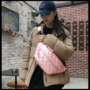 Detailed shot of pink quilted crossbody bag with metallic finish and woven zipper pull