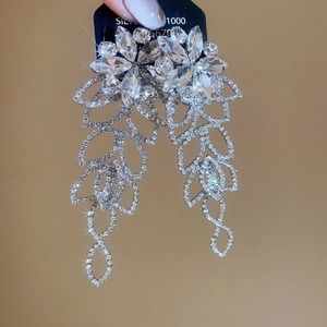 Vue détaillée de boucles d'oreilles argentées à pompon avec fleurs en cristal et feuilles