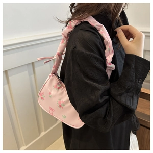 Detail showing pink floral handbag with red bow patterns on professional fashion model