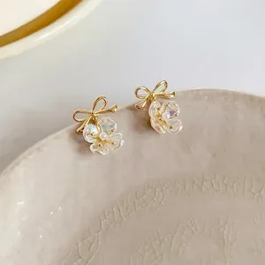 Elegant gold flower pearl earrings with bow design and iridescent petals on ceramic