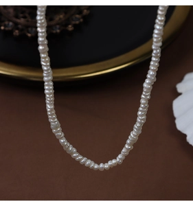 Elegant natural baroque pearl necklace detail on vintage tray with warm background lighting