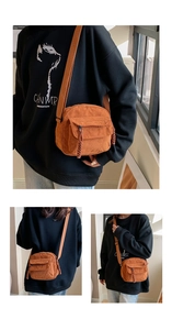 Detail of warm orange corduroy crossbody bag with vertical texture and zip front pocket