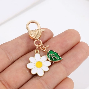 Detailed view of daisy keychain with white petals, green leaf, and golden heart clasp