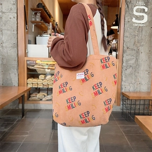 Detail of a large capacity corduroy tote bag with Keep Smiling print and logo patch