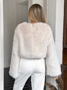 Vista posteriore di un elegante giacca corta in ecopelliccia beige con maniche oversize