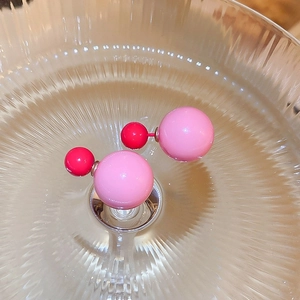 Macro view of double-sided pink resin bead earrings on textured glass surface