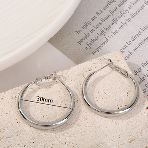 Minimalist silver hoop earrings with 30mm diameter shown on a textured stone base
