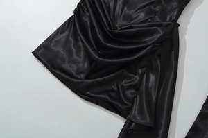 Détail de robe élégante en satin noir avec texture plissée et finition soyeuse premium