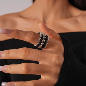 Detailed view of multilayer beaded ring featuring silver metal and black beads on finger