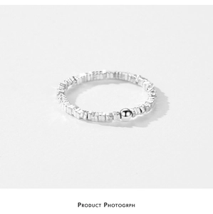 Detail of silver irregular beaded ring featuring small square elements and a smooth bead