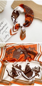 Detailed view of silk square scarf featuring orange horse carriage pattern and satin texture