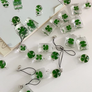 Flat lay of multiple clover resin pendants in round and rectangular shapes on white table