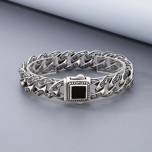 Dettaglio catena in argento vintage con motivi floreali e gemma nera quadrata incisa