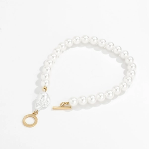 Macro detail of layered pearl bracelet featuring golden OT toggle clasp and baroque charm