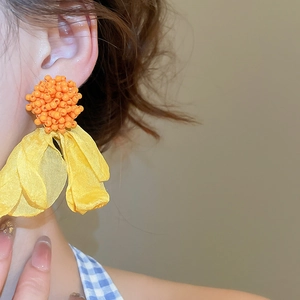 Close-up of vibrant yellow chiffon flower tassel earrings with orange bead details