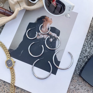 Three sizes of polished silver stainless steel hoop earrings on a fashion magazine background