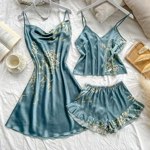 Detailed flat lay of three-piece silk satin floral pajama set with camisole and shorts