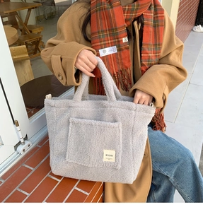 Close-up of off-white faux shearling tote bag with fuzzy texture and BYBR label detail