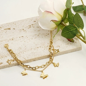 Double-layer 18K gold plated butterfly bracelet set on a textured travertine background