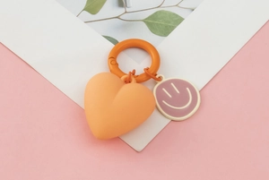 Detail of orange heart and purple smiley face keychain with spring buckle accessory