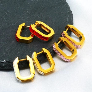 Detailed close-up of three gold titanium earrings with red, pink, and white cubic zirconia
