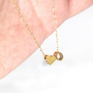 Dettaglio della collana con ciondolo a cuore e anello dorato su catena sottile