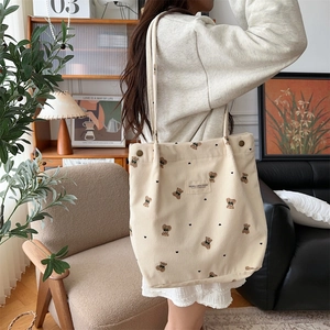 Detail of beige corduroy tote bag featuring a cute cartoon bear print and shoulder strap