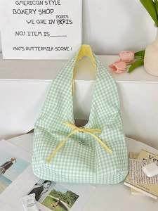 Green and white plaid canvas tote bag with yellow ribbon bow in a lifestyle setting