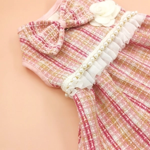 Close-up of pink tweed pet dress with camellia flower, pearls, and lace trim detail