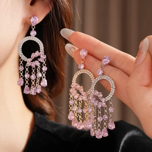 Close-up of dangling tassel earrings featuring pink teardrop stones in silver and gold