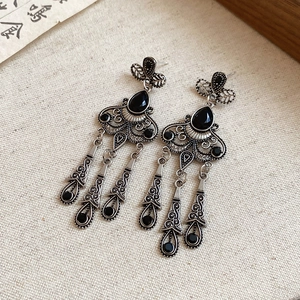 Detailed macro view of vintage hollowed flower earrings with black drop tassels