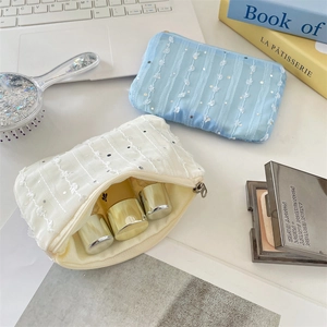 Close-up of sequin chiffon flower coin purses with makeup bottles on a desk
