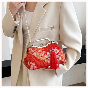 Detail of red floral brocade shell bag with pearl strap and decorative tassels