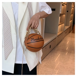 Detail view of brown basketball-shaped crossbody bag with gold chain strap and cursive text