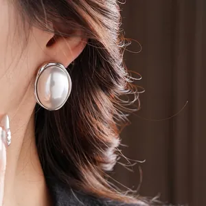 French vintage silver-edged oval pearl stud earrings on model with elegant style