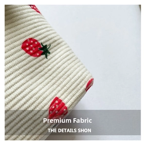 Close-up of white corduroy fabric with high-quality strawberry embroidery detail