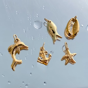 5-piece gold stainless steel ocean charm set featuring dolphin, anchor, fish, shell, and star