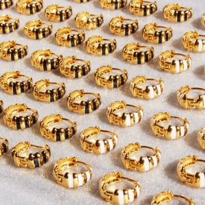 Minimalistische Creolen in Gold mit schwarz-weißem Emaille-Muster im Croissant-Design