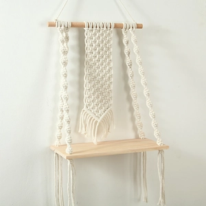 Detail of handcrafted macrame wall shelf with natural cotton rope and light wood board