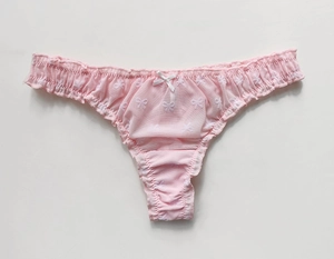 Detailed close-up of pink mesh thong with white bow print and delicate lace trim