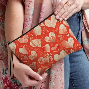 Red heart pattern makeup bag with black zipper and wristlet strap held by a model