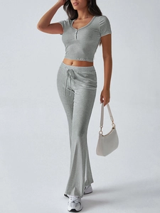 Dettaglio di un set a due pezzi in maglia grigia con top a maniche corte e pantaloni flare