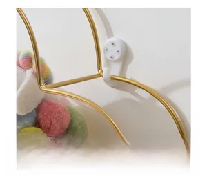Detail of gold metal wall shelf with colorful pom-pom decor and seamless wall mount nails