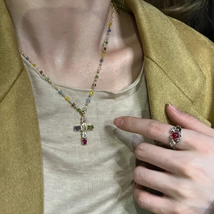 Collier croix en zircon coloré et bague en pierre rouge sur un modèle en costume jaune