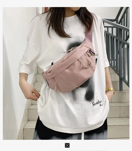 Close-up of pink nylon chest bag with adjustable strap worn by a model in a street style look